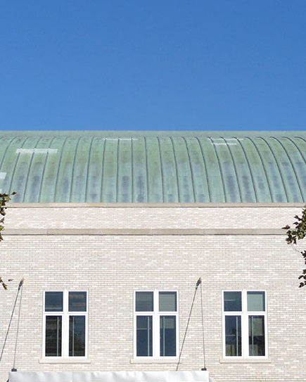 Building with a green verdigris roof under a clear blue sky. Patina kit from the paint laboratory.