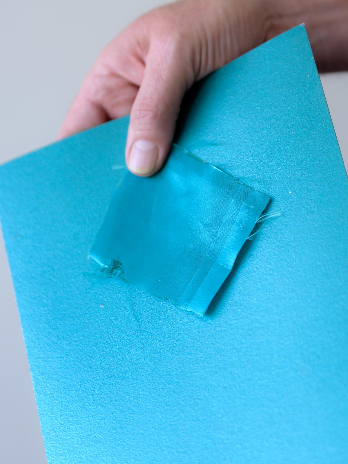 Teal fabric compared directly with a custom-matched painted color sample